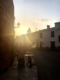 Street amidst buildings against sky during sunset