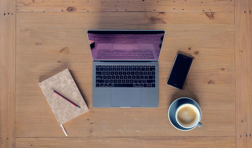 Directly above shot of laptop with mobile phone and coffee cup on table