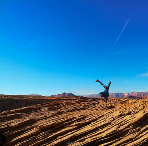 Man doing handstand on land against clear blue sky