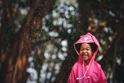 Cute girl looking away while standing during raining season