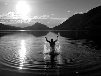 Silhouette people in lake against sky