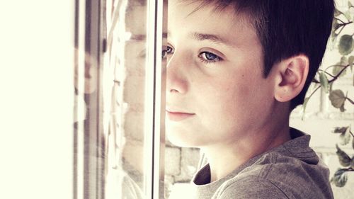 Close-up of boy standing by window