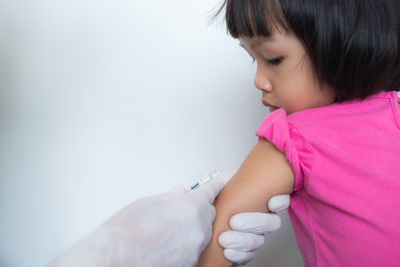 Cropped hands of doctor injecting girl by wall in hospital