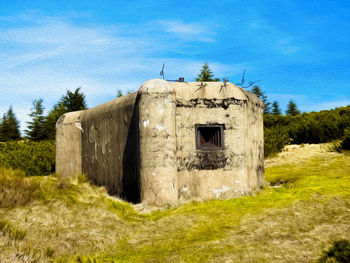 Old building on field against blue sky