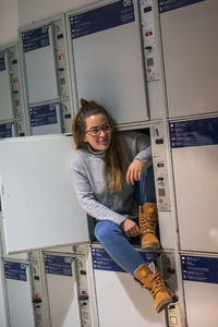 Full length of young woman sitting in locker