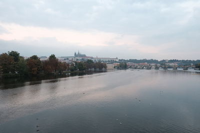 Scenic view of river by buildings against sky