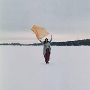 Woman standing by lake against sky during winter