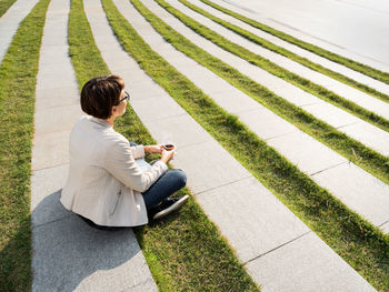 Woman in park with take away cup of coffee. casual clothes, urban lifestyle of millennials.