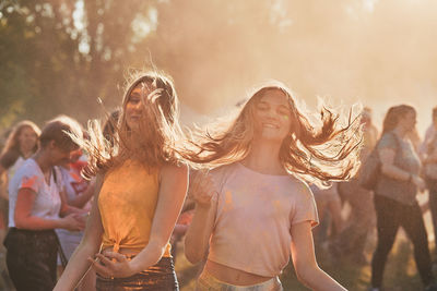 Portrait of teenage girls tossing hair while standing outdoors