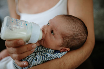 Midsection of woman feeding newborn son at home