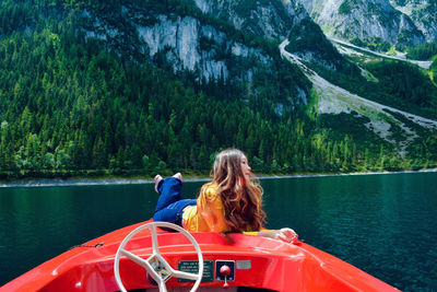 Woman sitting on boat in lake against trees in forest