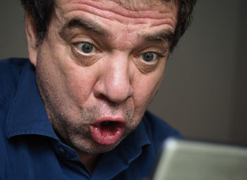 Close-up of surprised man looking at mobile phone