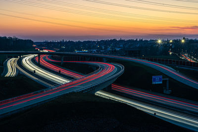 Light trails on road in city against sky during sunset