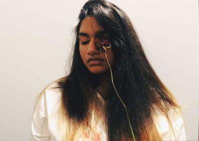 Young woman with dry rose against wall