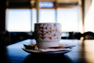 Coffee cup in plate on table at cafe