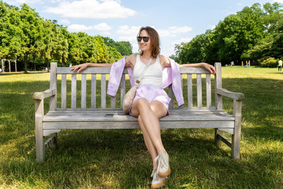 Portrait of young woman sitting on bench at park