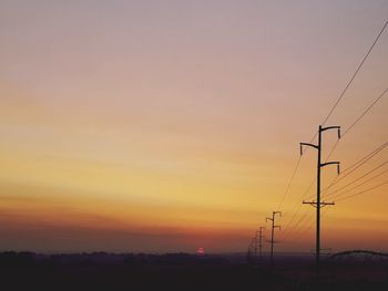 Silhouette electricity pylon against romantic sky at sunset