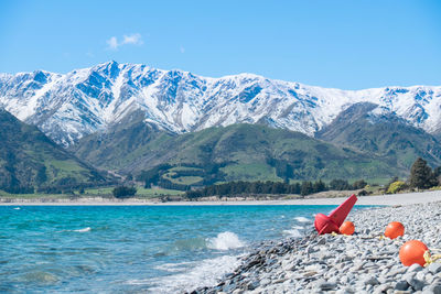 Scenic view of sea and snowcapped mountains against blue sky