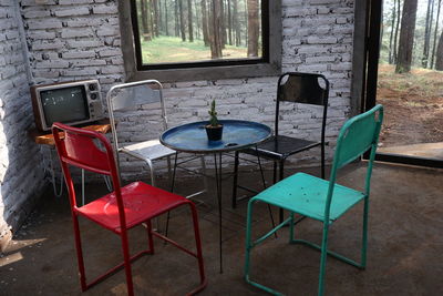 Empty chairs and table against window in old building