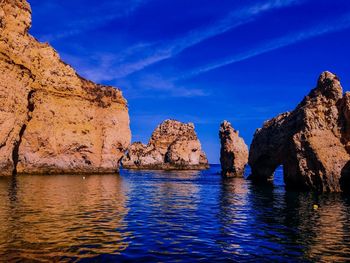 Rock formations in sea against blue sky