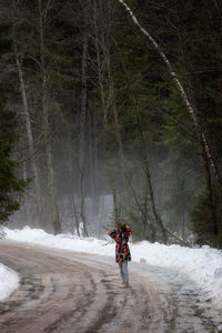 Rear view of man walking on snow covered landscape