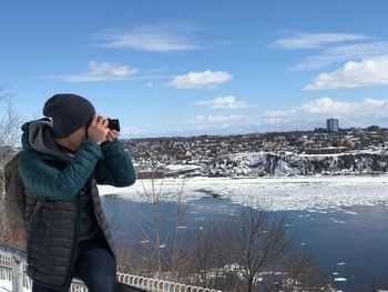 Man photographing against sky during winter