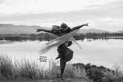 Man standing by lake against sky