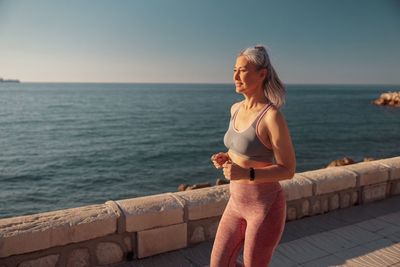 Portrait of young woman standing against sea