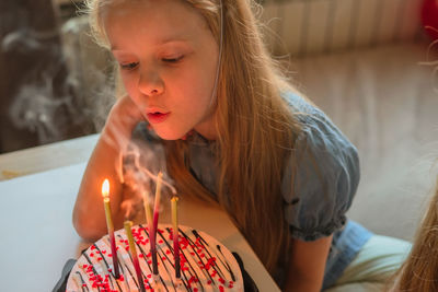 Little twin girls, children blow out candles cake birthday party at home. holiday during quarantine