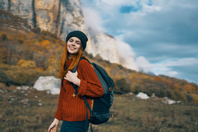 Portrait of smiling young woman standing against mountain