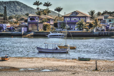 Boats moored at harbor against sky