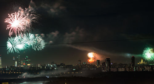 Firework display over illuminated buildings in city at night