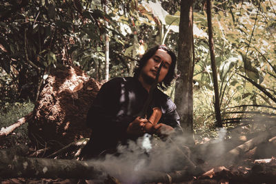 Portrait of young man sitting in forest