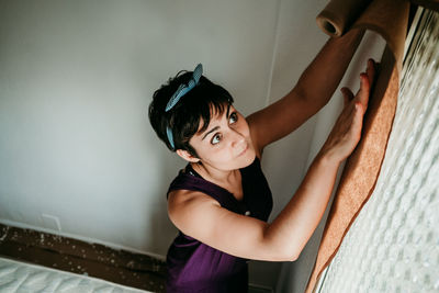 Portrait of smiling woman standing against wall at home