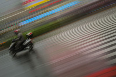 Blurred motion of people riding motorcycle on road