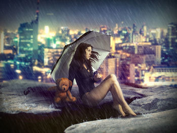 Woman sitting on wet glass in rain at night