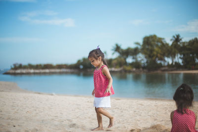 Rear view of girl on beach against sky