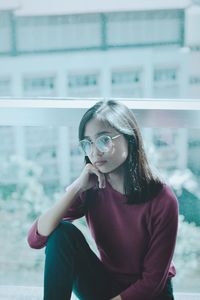 Young woman looking away while sitting outdoors
