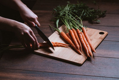 Cropped hand of woman cutting carrot