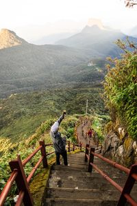 Hiker photographing mountains while standing on steps in forest