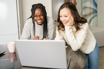 Smiling women looking at laptop at home