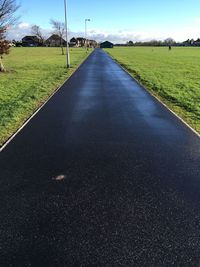 Road amidst field against sky