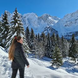 Woman standing on snow covered mountain against sky