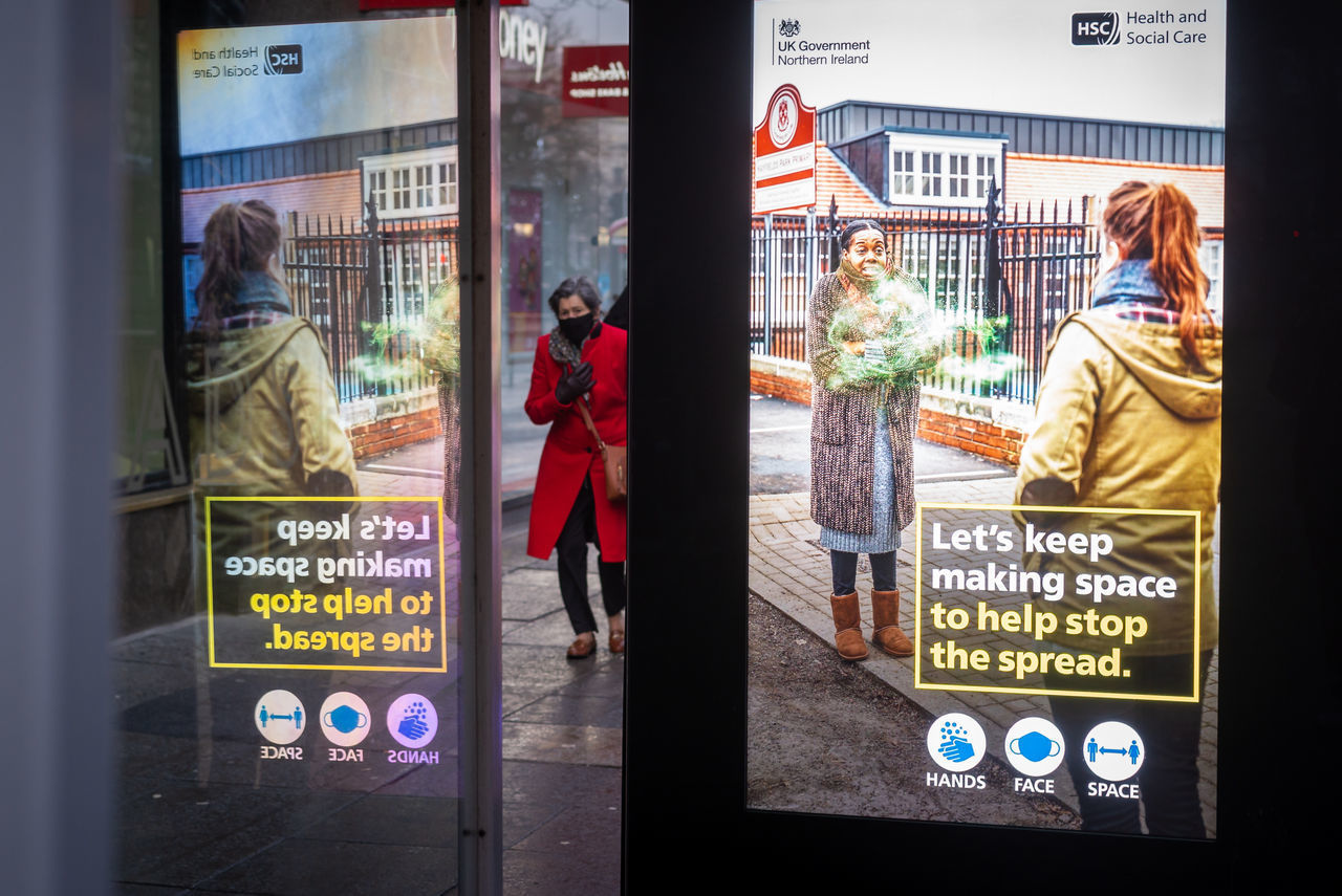 PEOPLE ON STREET SEEN THROUGH SIGN