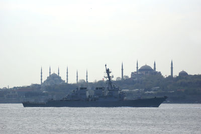 Boats in sea by buildings against clear sky