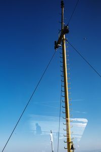 Low angle view of electricity pylon against blue sky