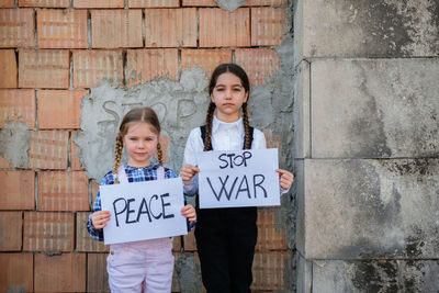 Portrait of girls holding banner against wall