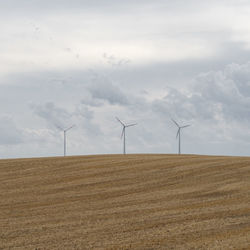 Wind turbines on field against sky