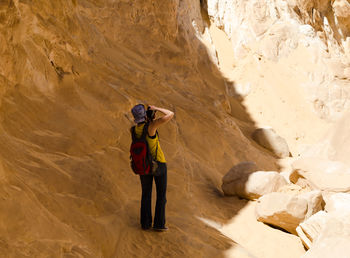 Rear view of woman photographing while standing by rock formation