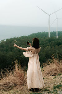 Rear view of woman photographing against sky